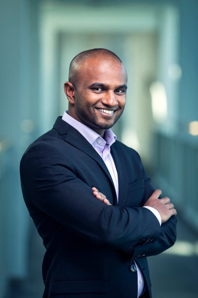 man-in-black-peaked-lapel-blazer-crossing-arms-2505053 Portrait of a confident businessman in a suit, smiling and posing indoors.