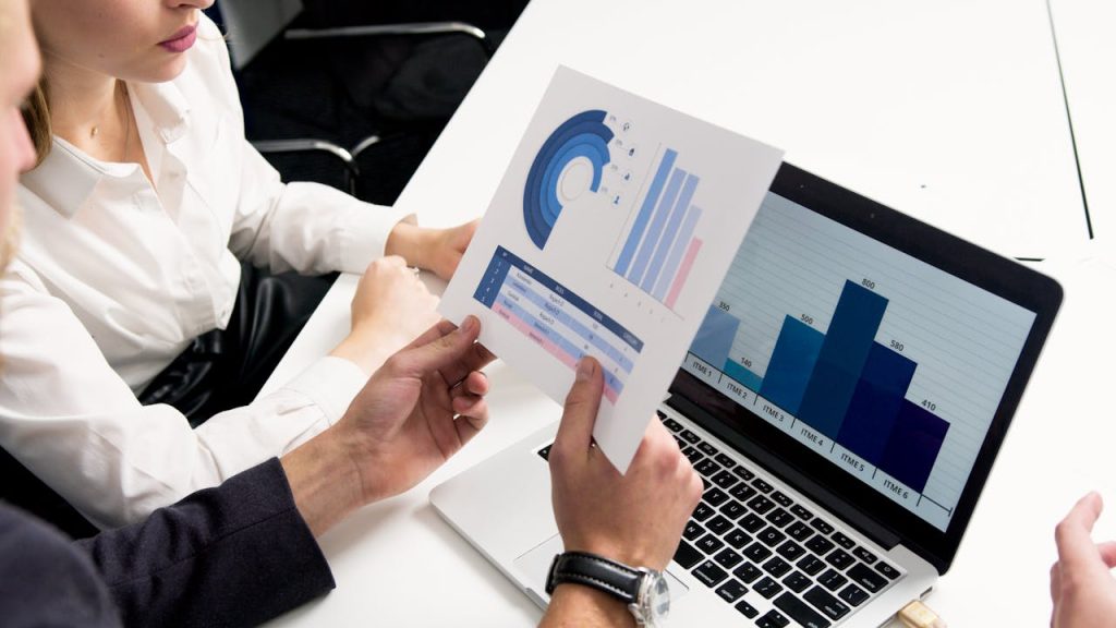 person-holding-white-and-blue-box-5716001 Business professionals discussing data charts and graphs in a modern office setting.